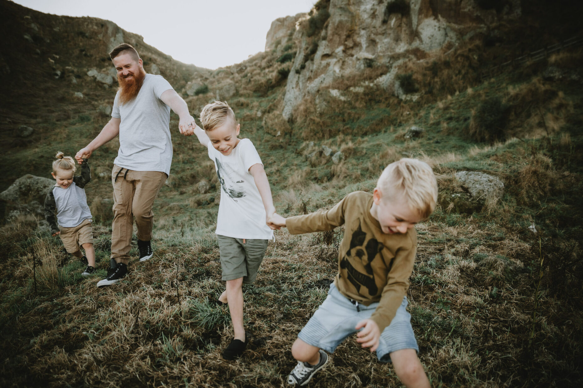 Dad having fun with his children outdoors on a hill running and laughing